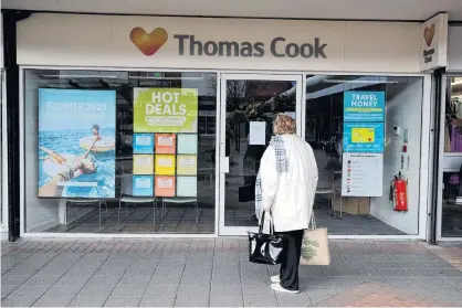  ?? PHIL NOBLE/REUTERS ?? A woman stands outside a closed Thomas Cook travel agents store near Manchester, Britain, earlier this month.