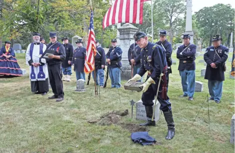  ?? MICHAEL SEARS / MILWAUKEE JOURNAL SENTINEL ?? Steve Michaels, the Milwaukee camp commander, shows the marker acknowledg­ing the Civil War service of Pvt. Charles Blanchard to be placed in front of the grave marker. Dean Collins, a Catholic deacon and the camp chaplain, is at left, and next to him...