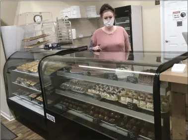  ?? BILL DEBUS — THE NEWS-HERALD ?? Tina Wyatt, owner of Cake Corner Bakery in Madison Township, poses behind the display cases filled with her freshly made cakes, cupcakes and other sweet delicacies.