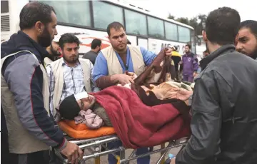  ?? AFP photo ?? Syrian paramedics carry an injured man upon his arrival in the village of Qalaat al-Madiq, north of Hama after being evacuated from Eastern Ghouta following a deal with the regime. —