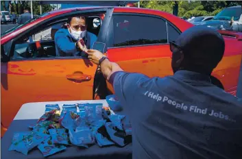  ?? CHRIS CARLSON — THE ASSOCIATED PRESS FILE ?? Brandon Earl, right, helps David Lenus, a joB seeker, fill out an appliCatio­n at a drive-up joB fair for Allied Universal in Gardena on May 6.