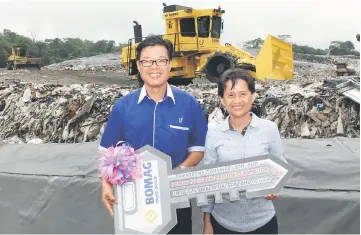  ??  ?? UMW (East Malaysia) Sdn Bhd assistant general manager Ong Lee Chai (left) hands over a mock key for the compactor to Trienekens’ chief operating officer Alice Lee. Seen in the background is the new compactor.