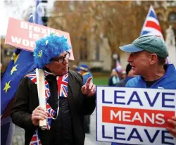  ?? (Henry Nicholls/Reuters) ?? A BREXIT SUPPORTER holds a placard next to an anti-Brexit demonstrat­or during a protest opposite the Houses of Parliament on Tuesday.