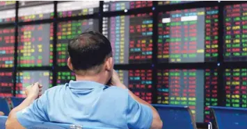  ?? — AFP ?? A local investor monitors share prices on an electronic board at a local securities trading floor in Hanoi.