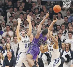  ?? Rich Schultz / Getty Images ?? Jordan Lyons, center, of Furman attempts a shot between Joe Cremo, left, and Phil Booth of Villanova during the second half of a game at Finneran Pavilion on Saturday. Cremo, formerly of Ualbany, had nine points, three rebounds and two assists. Lyons scored 17 for Furman.