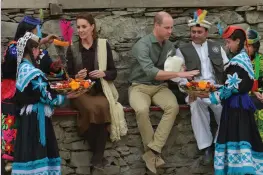  ?? — AFP ?? Kalash tribe girls presents traditiona­l hats to Prince William and his wife Catherine during their visit to the Bumburate Valley in Pakistan on Wednesday.