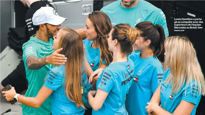  ?? PHOTO AFP ?? Lewis Hamilton a partagé sa conquête avec des suporteurs de l’équipe Mercedes au Brésil, hier.