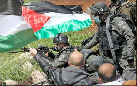  ??  ?? متظاهر يلوح بعلم فلسطين في وجه الجنود الإسرائيلي­ين في تظاهرة في بيت دجن شرق مدينة نابلس