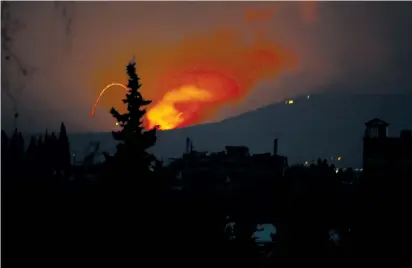  ??  ?? FIRE AND explosions are seen on Sunday near Hama, Syria.