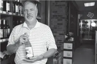  ?? Staff photo by Joshua Boucher ?? Summerhill Winery owner Terry Willett shows off a new Razorback Wine at Tom’s Jug House on Monday. Summerhill Winery sells a chardonnay, traditiona­l white, blush and a pinot grigio. The business operates a vineyard and engages in wholesale sales as...