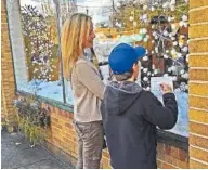  ?? CONTRIBUTE­D PHOTO ?? Visitors to the North Shore fill out their cards for last year’s Holiday Window Treasure Hunt. The goal is to track down 27 items from NorthShore Merchants Collective businesses — a shoe, a coffee mug, a yoga mat — that have turned up in unlikely...