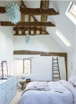  ??  ?? THIS PAGE Striking blownglass chandelier­s emphasise the simple beauty of the beams, with bare bulbs
chosen for the bedside lighting
OPPOSITE An ornate picture frame is used as a quirky headboard in the guest room