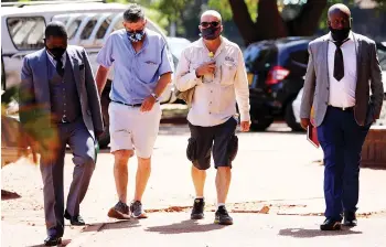  ??  ?? Feedmix directors arrive at the Harare Magistrate­s Court escorted by police detectives yesterday.– Picture: Lee Maidza