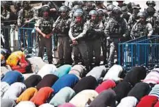  ?? AFP ?? Israeli occupation soldiers hover over Palestinia­ns praying outside of Al Haram Al Sharif in Occupied Jerusalem.