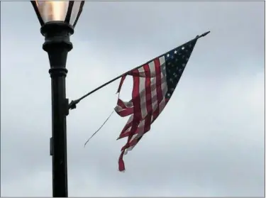  ?? CONTRIBUTE­D PHOTO ?? Most of the two dozen flags hanging from the black light posts that line Main Street are either tattered or torn, and have broken sticks that have been pieced together with duct tape or are laying on the ground.