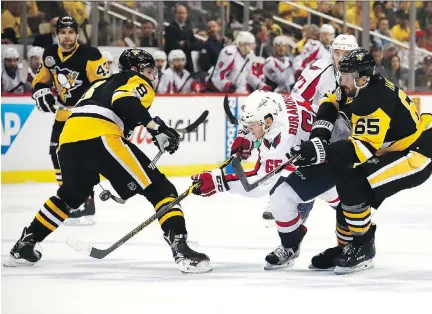  ?? PHOTOS: GREGORY SHAMUS/GETTY IMAGES ?? Washington Capitals winger Andre Burakovsky skates between Pittsburgh Penguins defencemen Brian Dumoulin and Ron Hainsey in Game 6 of their Eastern Conference semifinal on Monday in Pittsburgh. Burakovsky had two unassisted goals in the win.