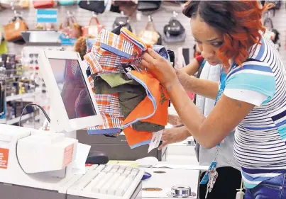  ?? ROGELIO V. SOLIS/ASSOCIATED PRESS ?? Crystal Bowman, manager of Citi Trends clothing store in Jackson, Miss., rings up school clothes and uniforms for a customer. The Commerce Department released positive retail sales data for July on Wednesday.