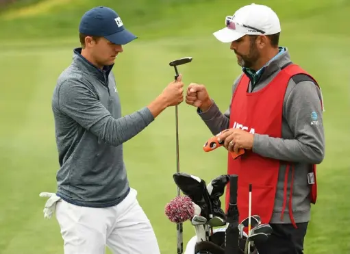  ?? Ross Kinnaird/Getty Images ?? Jordan Spieth and his caddie, Michael Greller, fist bump on the eighth green Friday at Pebble Beach.
