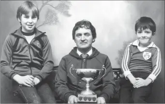  ??  ?? George O’Callaghan, then juvenile manager of Castleisla­nd FC, holding the Michael Colbert/James Horan Perpetual Cup for under-15 soccer league, with Richard Horan (left) and Michael Colbert Jnr.