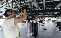  ??  ?? Rigger Jonathan Gaul installs lighting and sound equipment to the stage structure before hydraulic lifts are used to elevate the roof into position.