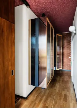  ??  ?? DANS LE COULOIR menant aux chambres, les armoires suspendues conçues par Eligo Studio combinent acier poli miroir et lattes verticales de chêne naturel et de verre.