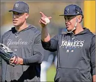  ?? David J. Phillip / Associated Press ?? Yankees Aaron Judge, left, and Giancarlo Stanton look to the stands before throwing out baseballs during a spring training workout Monday in Tampa, Fla. Judge says he’s OK with moving to left field when Stanton is playing in right.