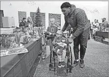  ?? [BARBARA J. PERENIC/DISPATCH] ?? Ohio State linebacker Malik Harrison guides Carson Roof, 7, and his older brother Cooper, 9, past tables of toys during the Buckeyes’ visit to Nationwide Children’s Hospital.