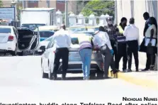  ?? NICHOLAS NUNES ?? Investigat­ors huddle along Trafalgar Road after police engaged gunmen in a fire fight on Monday. Two men were killed in the incident.