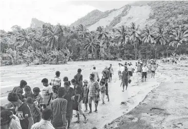  ?? Eranga Jayawarden­a / Associated Press ?? Sri Lankans trudge through the mud after a massive landslide Wednesday at Aranayaka. Landslides triggered by torrential rains crashed down onto three villages in the central hills of Sri Lanka, killing at least 37.