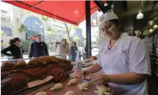  ??  ?? Sarah Haghighi makes turtle-shaped sourdough bread as passersby watch through a window at the Boudin Bakery located near Fisherman’s Wharf.