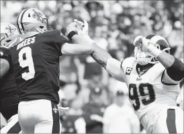 ?? Wally Skalij Los Angeles Times ?? DREW BREES hits the hand of Rams tackle Aaron Donald in the f irst quarter at the Coliseum, injuring his thumb. He didn’t play again. “I am concerned,” Brees conceded. “I’m hoping it’s not too signif icant.”