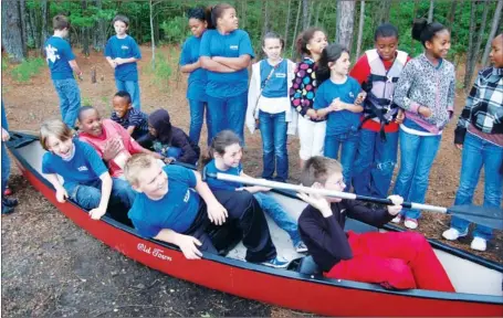  ?? WAYNE BRYAN/TRI-LAKES EDITION ?? Fourth-graders from Arkadelphi­a‘s Peake Elementary School gather in and around a canoe as students from Ouachita Baptist University relate the story of George Hunter and William Dunbar, two men who explored the Ouachita River in 1804 as part of...