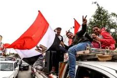  ??  ?? Egyptian boys flash the victory gesture and wave a national flag as they ride in the back of a pickup truck with speakers and posters forSisi, driving along a main street in the capital Cairo’s western Giza district, on the third day of the 2018...