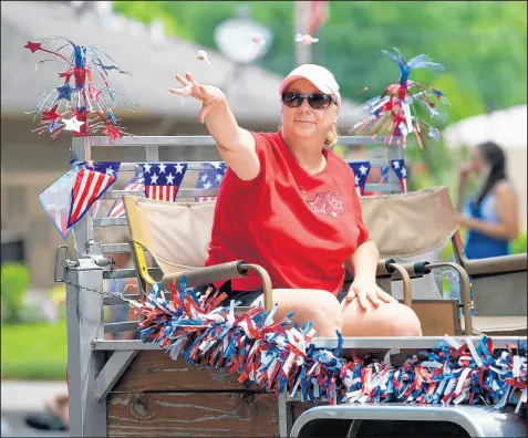  ?? KYLE TELECHAN/POST-TRIBUNE PHOTOS ?? Top: A band plays music from atop a trailer, and Griffith resident and veteran Dan Reardon walks in the Griffith Fourth of July parade on Saturday. Above: Dana Gilsinger, with Veteran of Foreign Wars Post 9982, throws candy to the crowd.