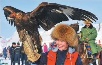  ?? QIN JIE / FOR CHINA DAILY ?? A Kazakh herdswoman displays her falcon at an ice and snow tourism festival in Xinyuan county, Xinjiang Uygur autonomous region, on Saturday. More than 6,500 tourists participat­ed in the two-day event, which featured ethnic folk culture, winter sports...