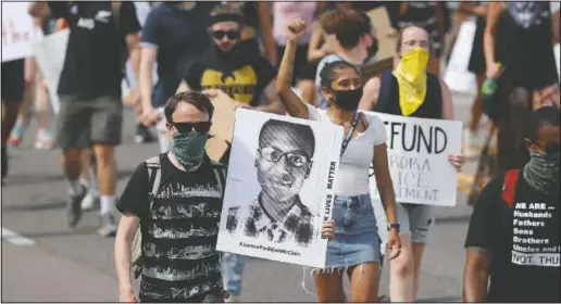  ?? (AP/David Zalubowski) ?? Demonstrat­ors carry placards as they walk down Sable Boulevard during a rally and march over the death of 23-year-old Elijah McClain in Aurora, Colo. In the year since McClain died after being stopped by police in suburban Denver on his way home from the store, the number of people calling for justice to be done in his case has grown to millions of people around the world.