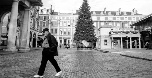  ?? AP ?? A man wearing a face mask passes the Christmas tree in Covent Garden Piazza, as England continues a four-week national lockdown to curb the spread of coronaviru­s, in London, Tuesday, November 17, 2020.