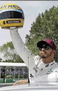  ??  ?? Lewis Hamilton exibe o capacete de Ayrton Senna, presente da família do brasileiro, após fazer a pole