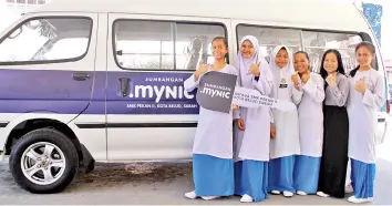  ?? - Bernama photo ?? SCHOOL BUS DONATION: Sekolah Menengah Kebangsaan Pekan II Kota Belud student Cornelia Limpun (sixth right) and friends react with the school bus donated by MYNIC Berhad worth RM100,000.