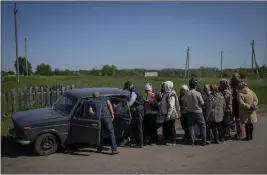  ?? BERNAT ARMANGUE — THE ASSOCIATED PRESS ?? Villagers line up to buy cigarettes and bread in the village of Staryi Saltiv, east of Kharkiv, Ukraine, on Friday. The village, formerly occupied by Russian forces, is back under Ukrainian control, albeit very close to the front line and under constant shelling.