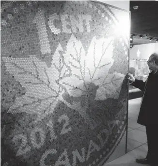  ?? ERIKA STARK, THE OTTAWA CITIZEN ?? Visitor Sheldon Dankner tries to determine how many pennies are in the mural at the Currency Museum of the Bank of Canada. (There are 16,500.) The exhibit runs until July 2.