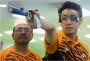  ??  ?? Johnathan Wong Guanjie training at the National Sports Council shooting range in Bukit Jalil while his coach Hashim Desa looks on.