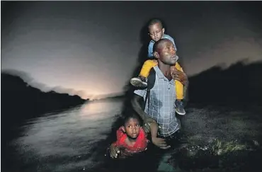  ?? Carolyn Cole Los Angeles Times ?? A HAITIAN MAN with children wades across the Rio Grande in Del Rio, Texas. Migrants who pass through another country and do not seek asylum there first before arriving at the U.S. border are ineligible for asylum.