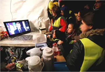  ??  ?? Protesters wearing yellow vests watch Macron on a TV screen at the motorway toll booth in La Ciotat, near Marseille. — Reuters photo