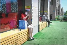  ?? — AFP photos ?? A woman uses her mobile phone as she rests on a bench outside a mall at a business district in Beijing.