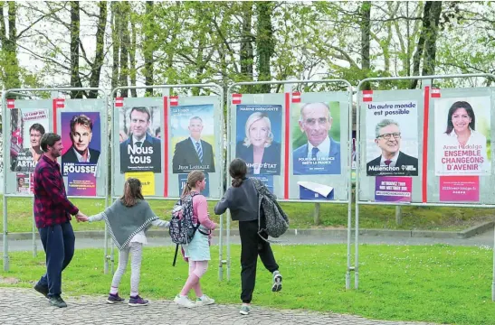  ?? AP ?? Una familia observa los carteles de los candidatos presidenci­ales en Mouguerre, en el sur de Francia