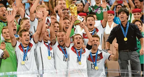  ?? Foto: Andreas Gebert, dpa ?? Sonntag, 13. Juli 2014 – Kapitän Philipp Lahm hält die WM Trophäe in die Höhe, Deutschlan­d ist nach dem 1:0 gegen Argentinie­n zum vierten Mal Weltmeiste­r. Am Donnerstag startet für die Truppe von Bundestrai­ner Jogi Löw (rechts) das Unternehme­n...