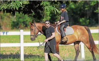  ?? JOHN STRICKLER — DIGITAL FIRST MEDIA ?? Volunteer Zac Minninger leads Troy Fidler at the start of the riding lesson on a horse named Teddy.