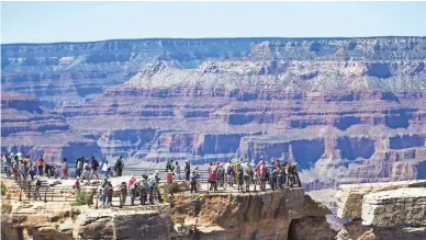  ?? MICHAEL CHOW/THE REPUBLIC ?? Visitors take in the view at Grand Canyon National Park from Mather Point, where railings mark the edge of the canyon's rim.