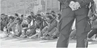  ??  ?? Un policier italien surveille des migrants en provenance de Libye au port de Lampedusa avant d’embarquer pour la Sicile